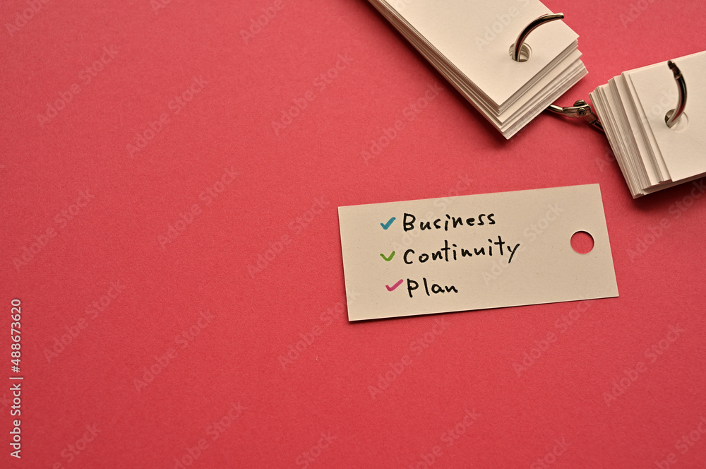 Poster there is a small card placed on a red background paper with the word business continuity plan writte
