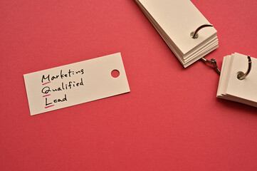There is a small card placed on a red background paper with the word Marketing Qualified Lead...