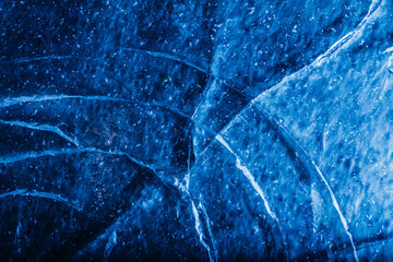 Photo of blue toned frozen crack line and damaged ice surface texture.