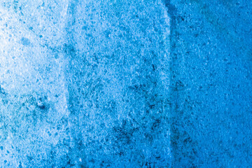 Photo of blue toned frozen transparent ice surface with snow texture.