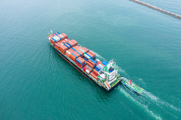 Aerial top view of cargo ship carrying container for import export goods send to customer from cargo yard port and running with tug boat  ,concept logistic and supply chain