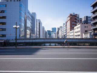 Fototapeta na wymiar a man riding bicycle on the asphalt road bridge on the river and tokyo cityscape background 