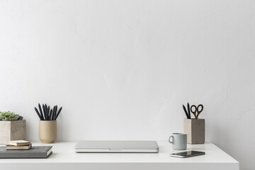 Laptop on a table at home office against white wall. Stylish minimalist workspace.	
