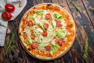 Pizza Caesar with chicken, salad and tomatoes on old wooden table top view