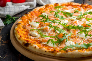 Pizza with salmon, Philadelphia cheese and aragula on old wooden table macro close up