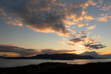 Fototapeta na wymiar Sunset Over Orcas Island, Washington. Located in the San Juan Islands this drone view and dramatic clouds was taken from Lummi Island looking across Rosario Strait in the Salish Sea.