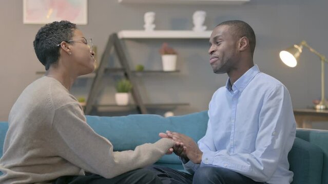 Loving African Man Talking to African Woman while Sitting on Sofa 