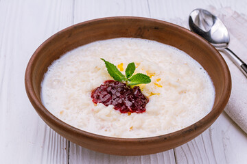 rice porridge with berry jam on bowl on white wooden table