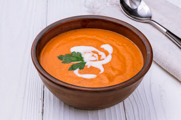 Soup cream of tomato on bowl on white wooden table