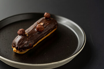 dessert is a small puff pastry pie with stuffing inside on a black serving plate on a black background . A piece of cake with a cut