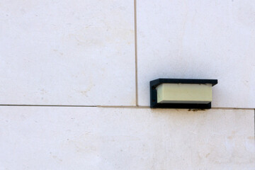 Black wall lamp installed on white marble wall