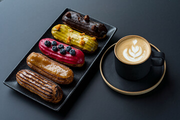 Fototapeta na wymiar Delicious eclairs, on a dark plate on a dark background. Space for copying. Sweets