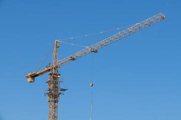 View of a tower crane installed at a construction site on a clear sky background