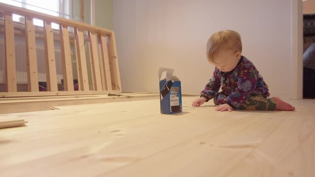 DIY, FAMILY - cute shot of a 1 year old fiddling with nails on a new floor being laid