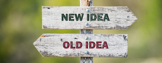 opposite signs on wooden signpost with the text quote new idea old idea engraved. Web banner format.