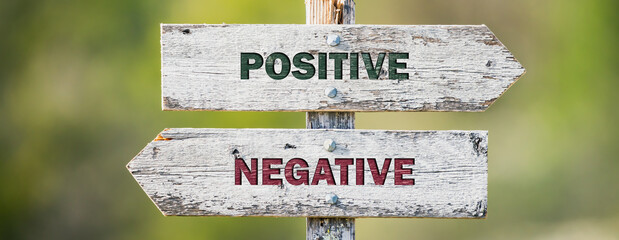 opposite signs on wooden signpost with the text quote positive negative engraved. Web banner format.