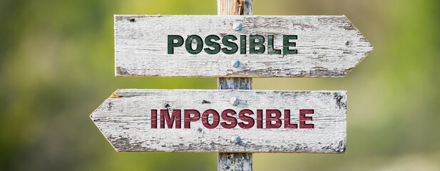opposite signs on wooden signpost with the text quote possible impossible engraved. Web banner...