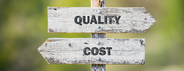 opposite signs on wooden signpost with the text quote quality cost engraved. Web banner format.
