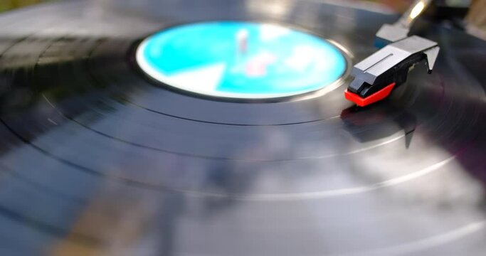 Turntable is spinning with a phono cartridge on the Vinyl. Vintage music player in the garden.