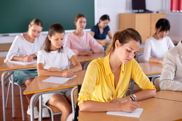 Students doing test in college, writing in notepads during lesson