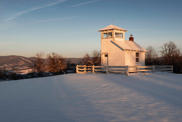 The rising sun illuminates a historic fire lookout tower and the eastern ridges of Shenandoah...