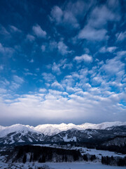 高台からの朝方の冬景色、白銀の街並みと白馬連峰を見渡す、青空には一面のウロコ雲が広がっている。