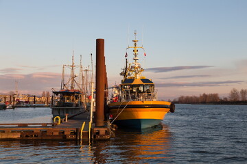Fototapeta premium Boats docked in the Steveston heritage fishing village marina at the mouth of the Fraser River during a golden hour winter sunset, Richmond, British Columbia, Canada