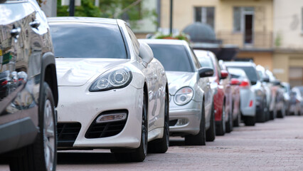 Cars parked in line on city street side. Urban traffic concept