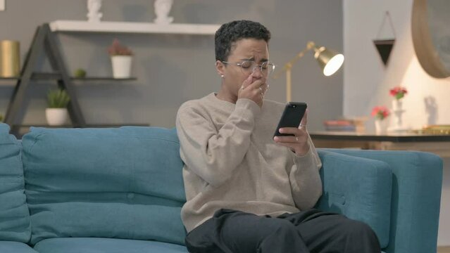 African Woman having Loss on Smartphone at Home 