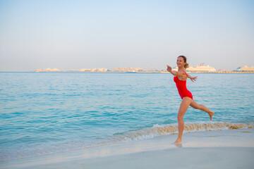 woman in red bikini jumping on the beach