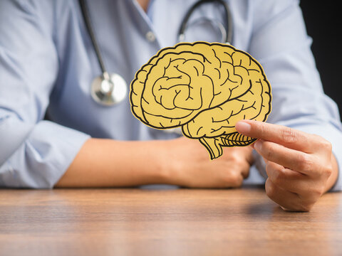 Doctor holding a brain shape made from yellow paper