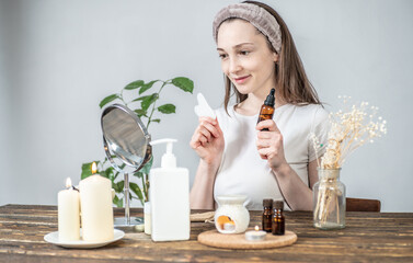 Young woman is holding a gouache scraper massager and a bottle of natural organic oil for massage...