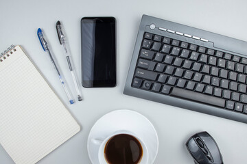 Coffee at work or office, a cup of coffee on the desktop, computer keyboard and office supplies, top view, space for text