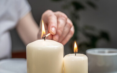 Woman is lighting candles to create a relaxing atmosphere, harmony and balance. Concept of...