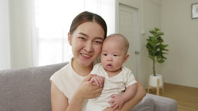 Point of view, Young Asian mother and her newborn baby smiling and say hello, goodbye via video call or facetime feeling happy