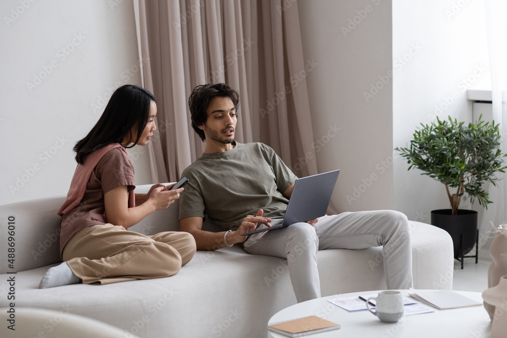 Aufkleber two young confident employees looking at laptop screen while sitting on sofa and analyzing online da