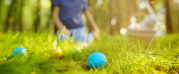 Little boy hunting for egg in spring garden on Easter day. Traditional easter festival outdoors....
