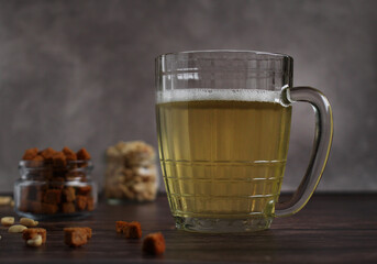 light beer in a glass mug with crackers and peanuts on a dark background