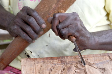 A close up of a skilled woodworker craftsman hands and woodworking tools, wooden mallet and chisel, carving a new piece of art in Bougainville, Papua New Guinea