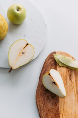 Pears and an apple with marble and wooden boards. Top view.