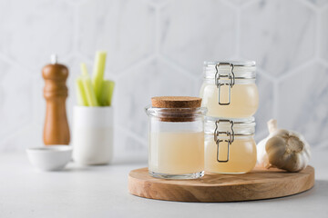 Bone broth soup in glass jars for storage on a wooden board. The concept of healthy eating.
