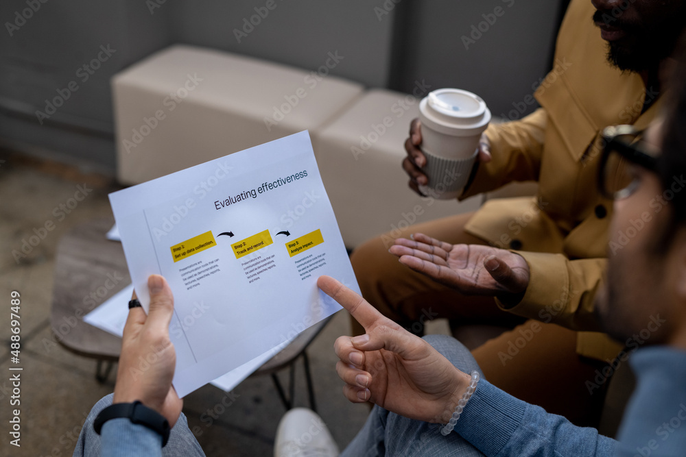 Aufkleber hand of young confident businessman pointing at business document while analyzing data and explainin