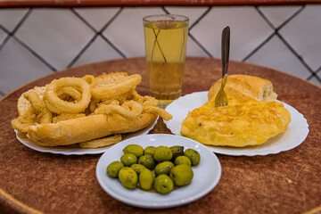 Spanish tortilla and fried calamari with green olives and cider in Madrid, Spain