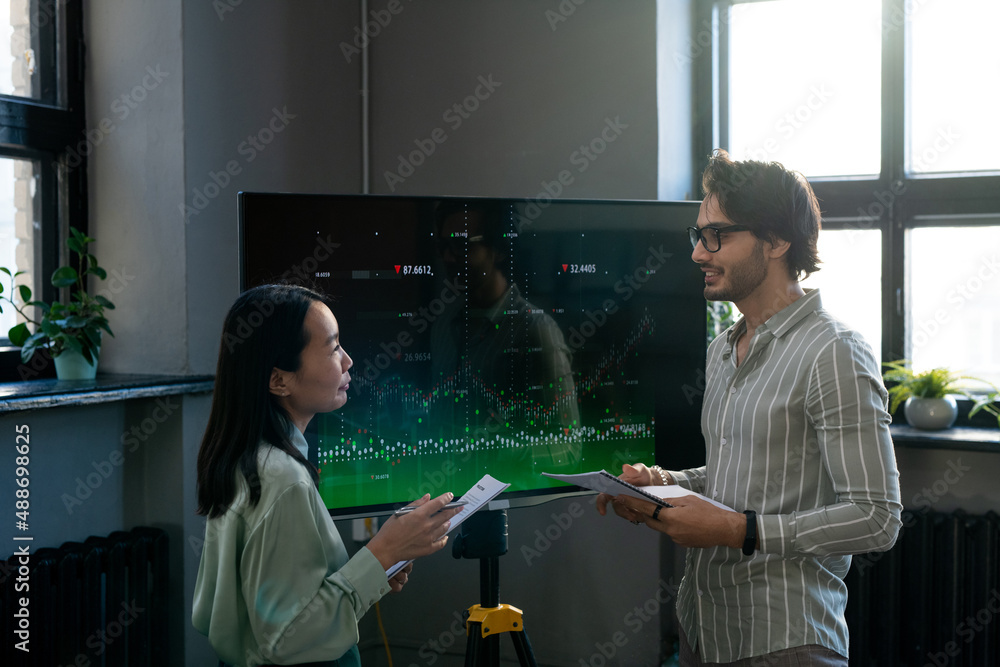 Aufkleber Two young confident analysts with documents discussing interactive financial data while businessman explaining something to female colleague
