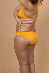 Cropped vertical photo of overweight fat woman with obesity hips, excess fat yellow swimsuit. Big...