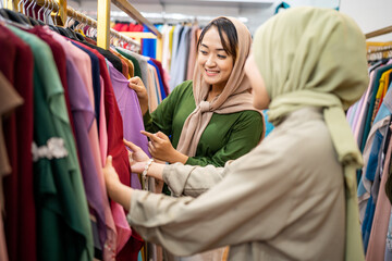 Beautiful muslim female with head scarf looking at a dress