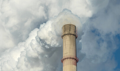 Powerful industrial factory chimney is smoking and polluting the environment with carbon dioxide