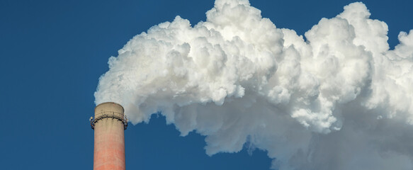 Powerful industrial factory chimney is smoking and polluting the environment with carbon dioxide