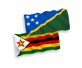 National vector fabric wave flags of Solomon Islands and Zimbabwe isolated on white background. 1 to 2 proportion.