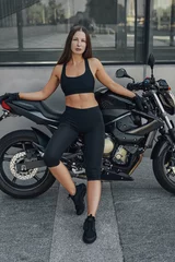 Foto op Plexiglas Brown haired sportswoman with black motorcycle outdoors © Fxquadro